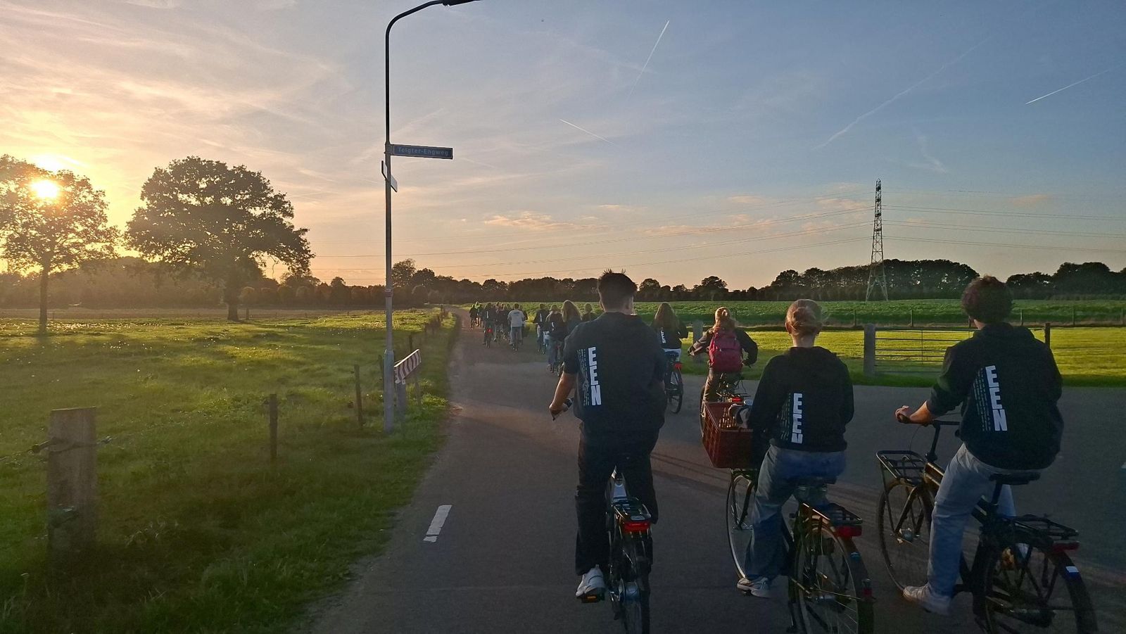 Jongeren van JA! fietsen samen bij zonsondergang tijdens het jeugdweekend