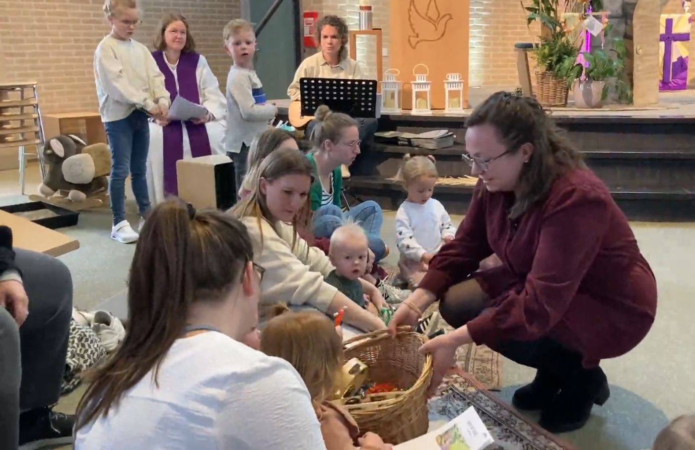 Kinderen en ouders zitten samen voorin de kerk tijdens Kerk op Schoot
